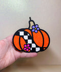Checkered Pumpkin Freshie in orange glitter with black outlines, white checkerboard stripe, and colorful flower accents