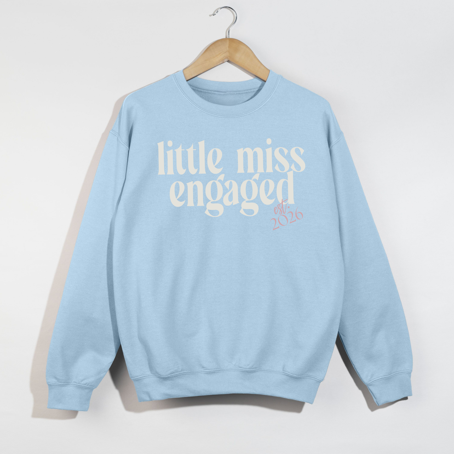 Little Miss Engaged light blue fleece sweatshirt with white script lettering and pink Est. 2026 detail