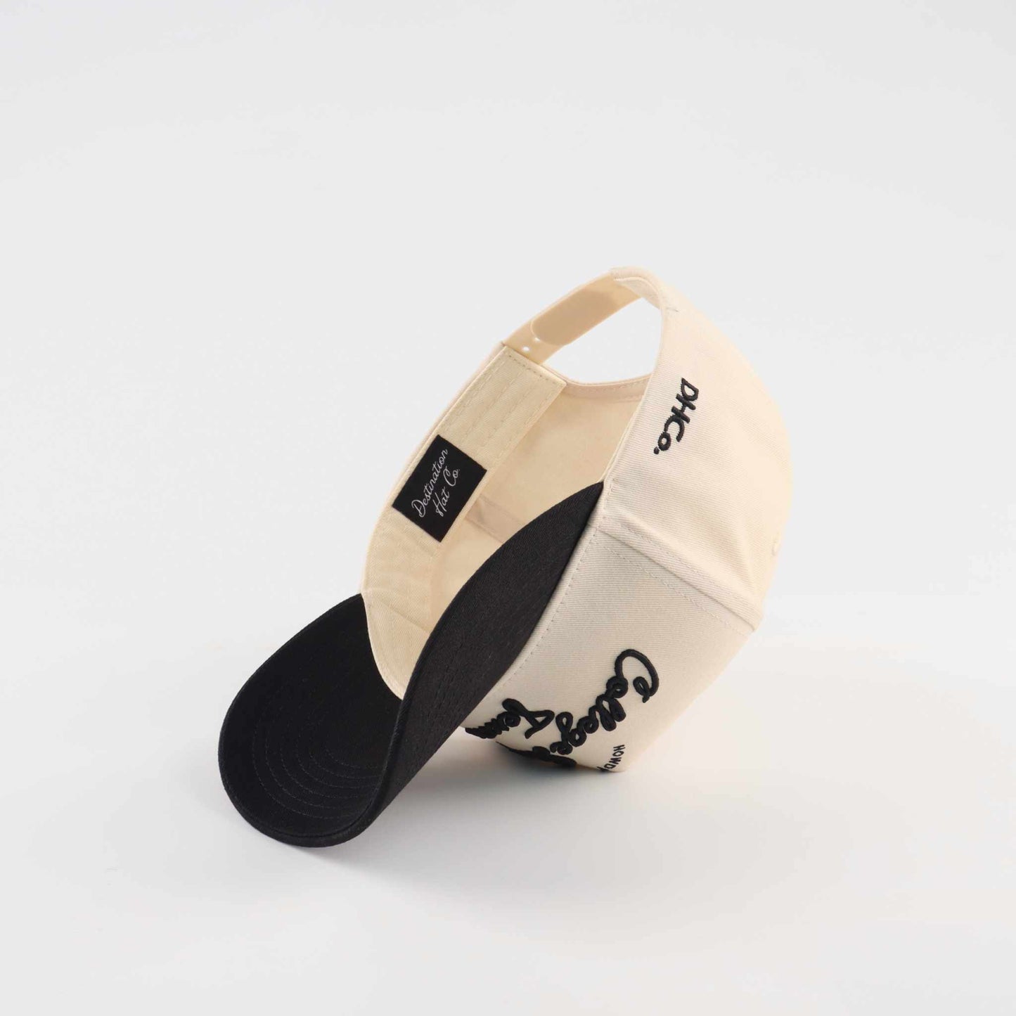 Pre-curved Trucker hat in beige and black with College Station script lettering and a curved black brim