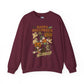 A maroon crewneck sweatshirt featuring a colorful 'Happy Halloween' graphic print on the front with cartoon illustrations of a witch, pumpkin, ghosts, and a skeleton.