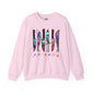 A light pink crewneck sweatshirt featuring a graphic of six knives with colorful tie-dye patterns and the word 'FRIENDS' printed below in a rainbow gradient, displayed on a clean white background.