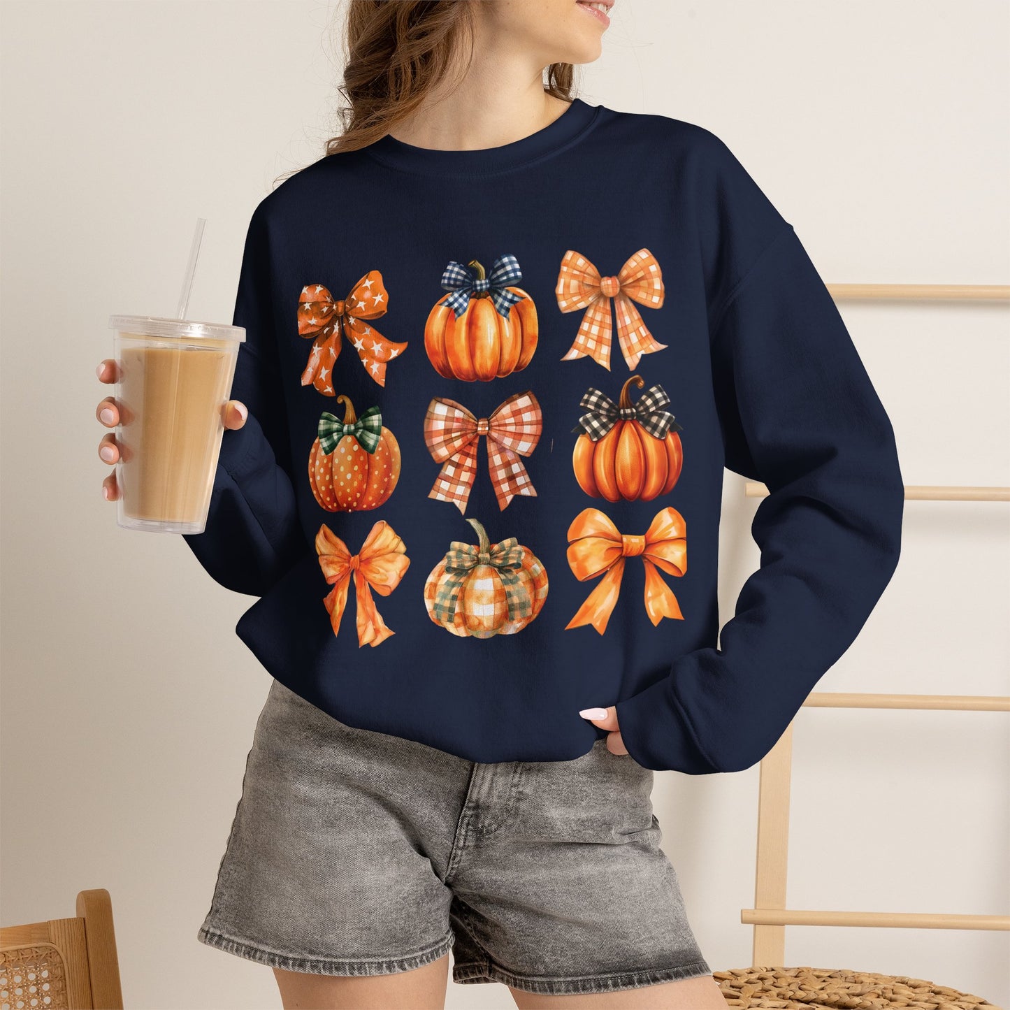 Person wearing a navy sweatshirt with pink text and a cartoon character, holding a drink.