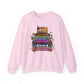 A light pink crewneck sweatshirt featuring a colorful graphic print on the front with cartoon characters and Halloween-themed VHS tapes text including 'Halloween', 'Hocus Pocus', and 'Casper'.