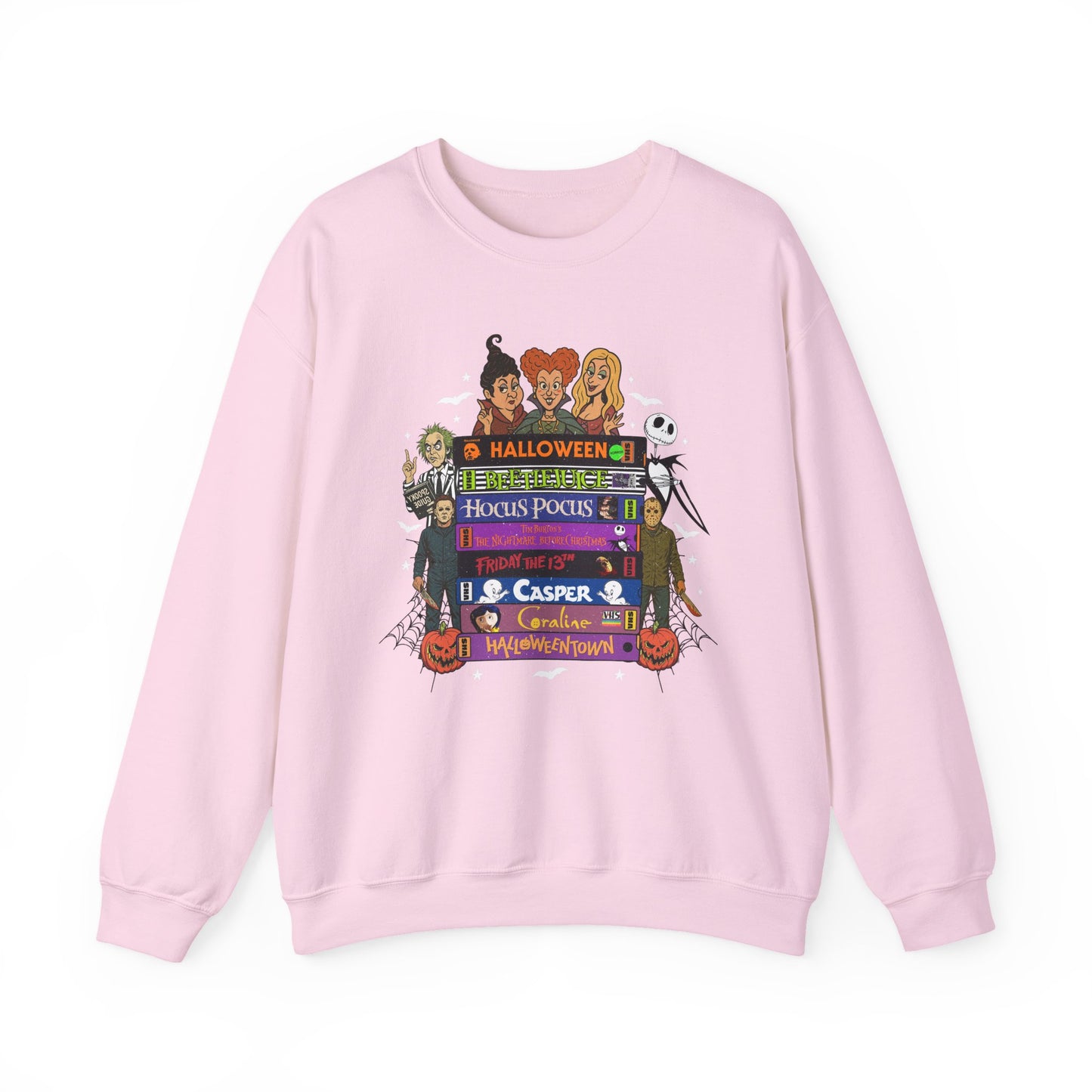 A light pink crewneck sweatshirt featuring a colorful graphic print on the front with cartoon characters and Halloween-themed VHS tapes text including 'Halloween', 'Hocus Pocus', and 'Casper'.