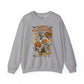 A heather gray crewneck sweatshirt featuring a colorful 'Happy Halloween' graphic print on the front with cartoon characters, ghosts, a pumpkin, and a skeleton.