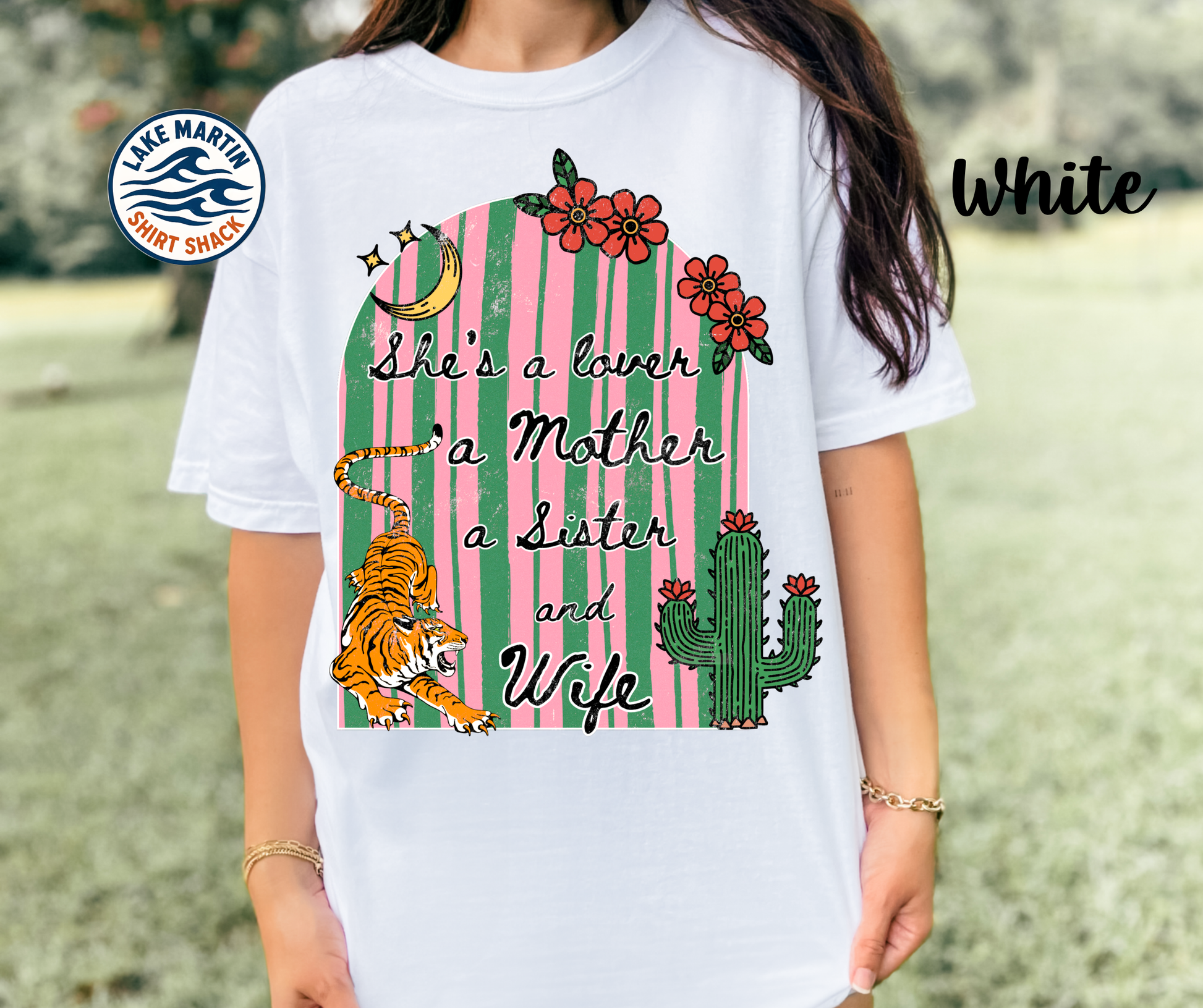 White t-shirt with a colorful graphic design featuring a cactus, tiger, and text, worn by a person outdoors.