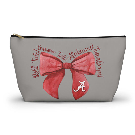 Crimson Bow Alabama script accessory pouch with vibrant red bow and gold zipper puller standing upright on a muted background