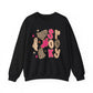 A black crewneck sweatshirt featuring a 'Spooky' graphic print with pink and leopard-print lettering and cute ghost illustrations, displayed on a clean white background.