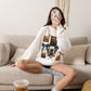 Woman wearing a white crewneck sweatshirt featuring a vintage witch-themed Halloween collage with black bows, bats, pumpkins, and orange accents.