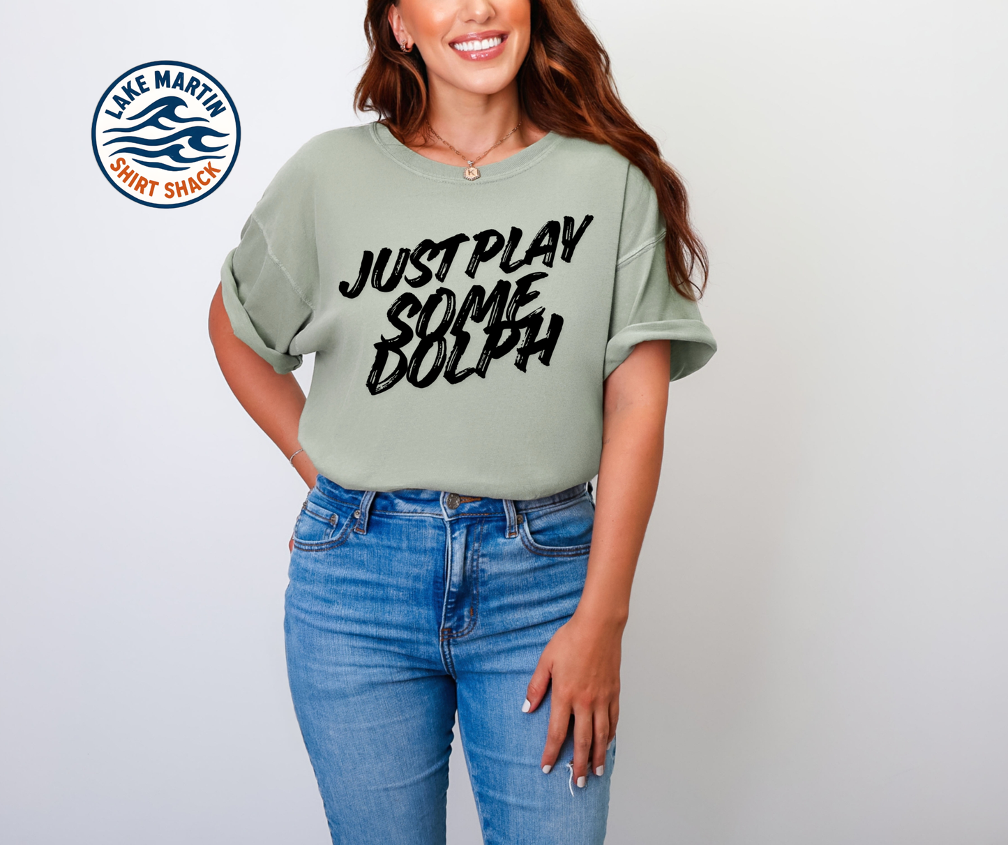 Woman wearing a green t-shirt with 'Just Play Some Dolph' text and blue jeans, standing against a white background.