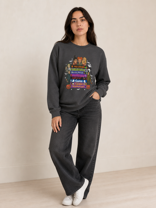 Woman modeling a dark heather crewneck sweatshirt featuring a colorful Halloween movie VHS stack graphic.
