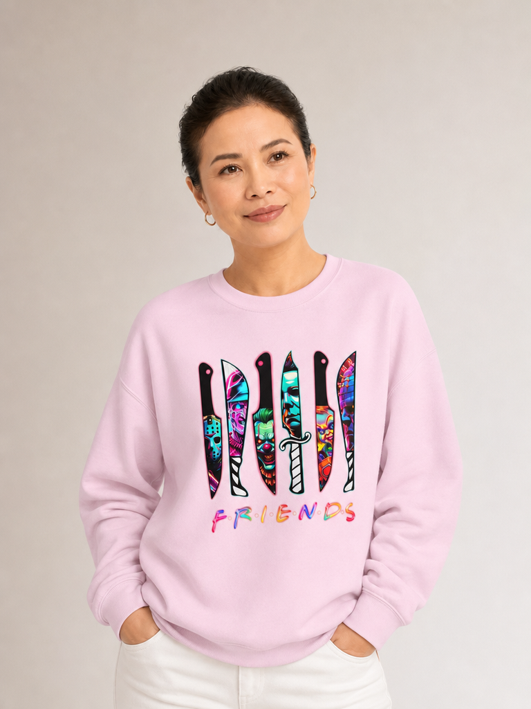 Woman modeling the front of a light pink crewneck sweatshirt featuring colorful horror-themed knives and the word “Friends.”