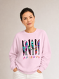 Woman modeling the front of a light pink crewneck sweatshirt featuring colorful horror-themed knives and the word “Friends.”
