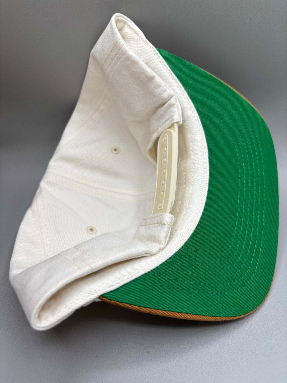 Alabama Crimson Tide snapback hat with white cotton crown, green brim, and contrasting brown edge