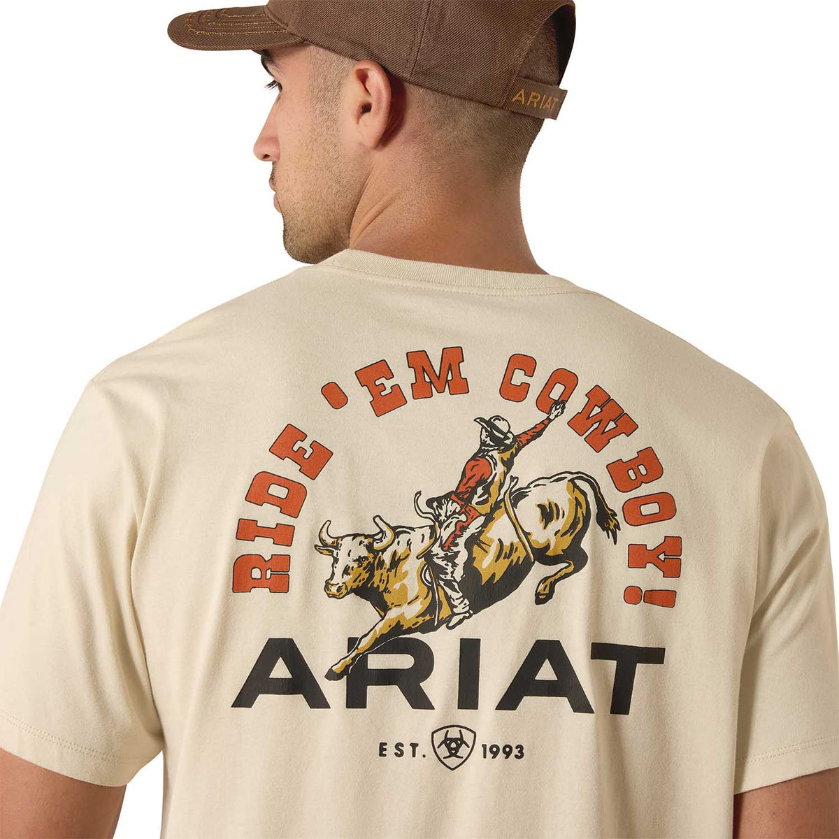 Ariat Mens Short Sleeve Shirt in beige cotton with a bold "Ride 'Em Cowboy!" graphic featuring a rodeo cowboy on a bull and Ariat branding.