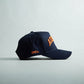 Navy blue snapback hat with orange 3D "AUBURN" embroidery and side stitch details, featuring Auburn Alabama Legacy branding.