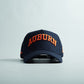 Navy blue snapback cap with bold orange 3D "AUBURN" embroidery, curved bill, and Auburn Alabama Legacy design.