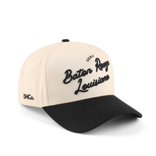 Baton Rouge script trucker hat in beige and black, featuring embroidered lettering and a pre-curved brim