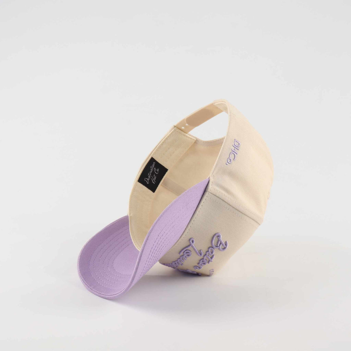 Trucker hat in beige and lavender with pre-curved brim and embroidered “Callin’ Baton Rouge!” script lettering