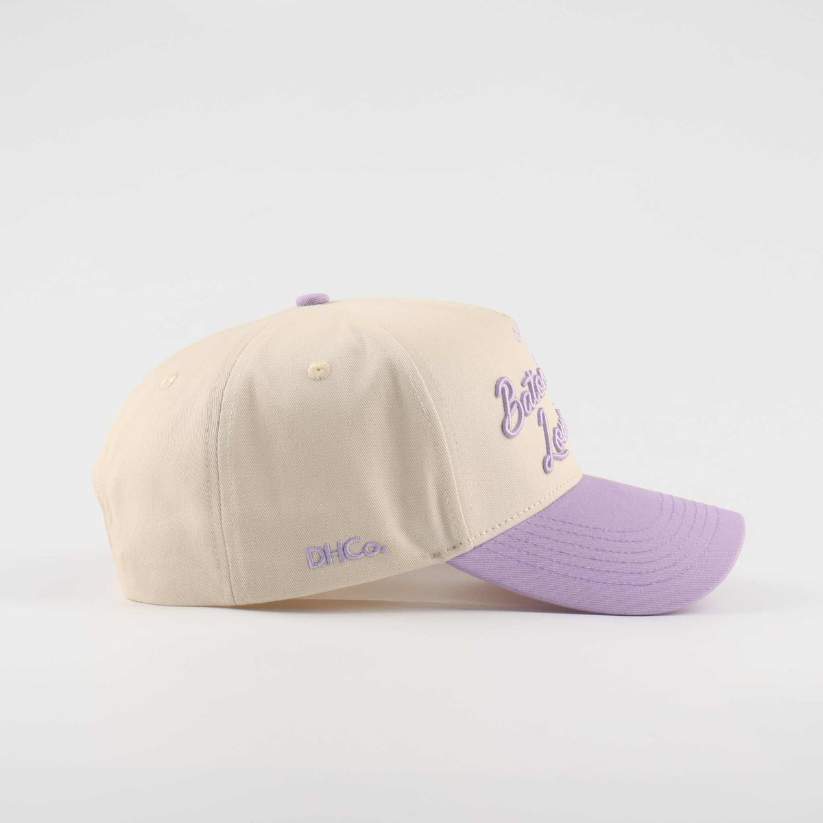 Baseball cap in beige and lavender cotton, with a pre-curved brim and embroidered “Callin’ Baton Rouge!” script.