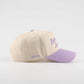Baseball cap in beige and lavender cotton, with a pre-curved brim and embroidered “Callin’ Baton Rouge!” script.