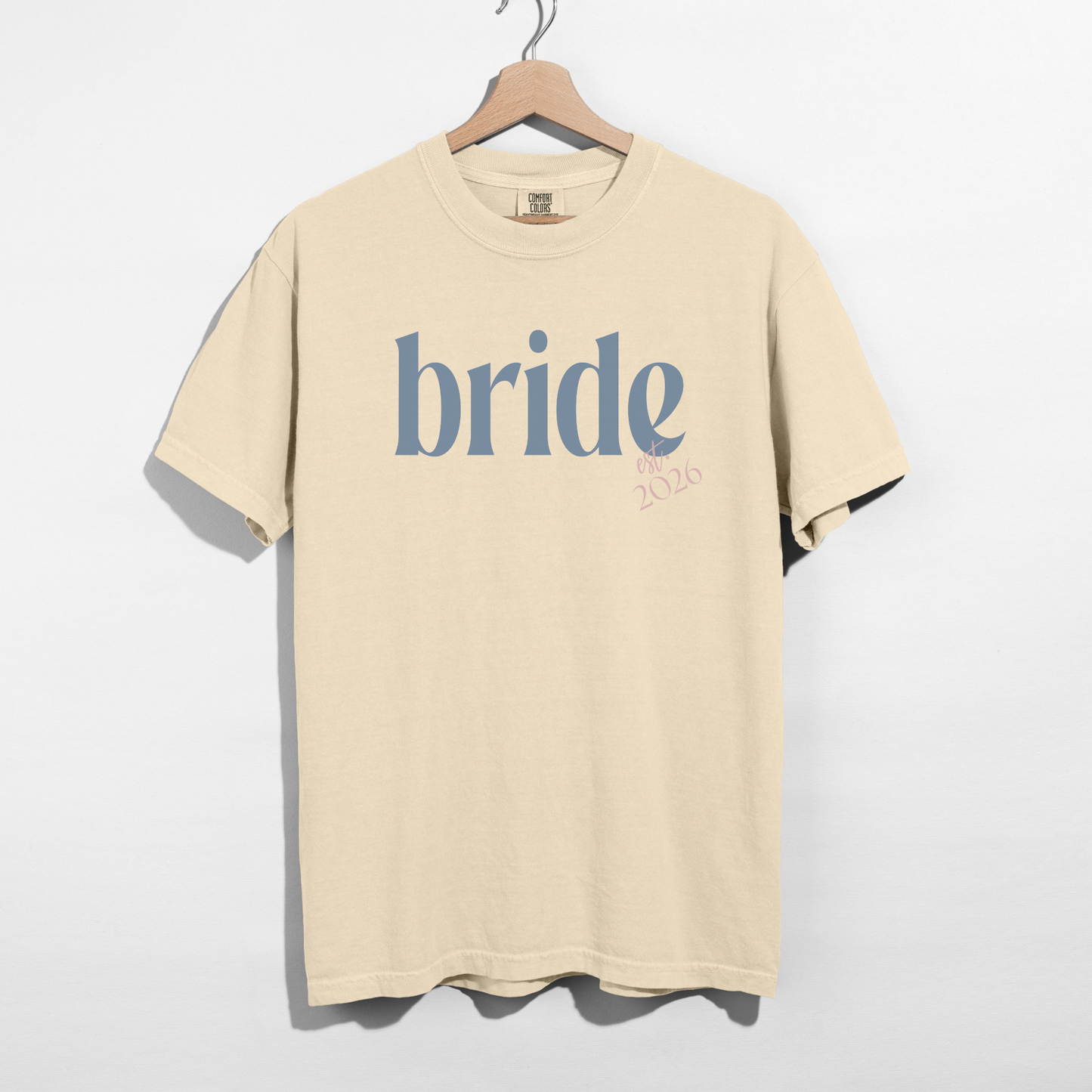 Bride Est. 2026 tee in cream cotton with blue serif bride lettering and pink 2026 detail