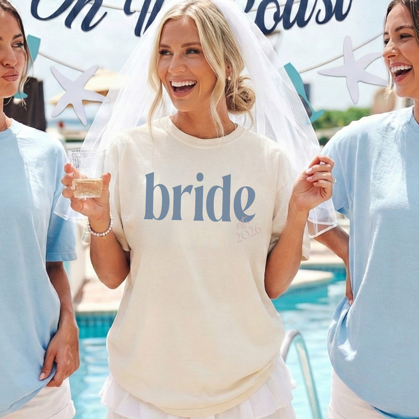 Bride Est. 2026 ivory cotton t-shirt with blue serif bride lettering and pink embroidered-style date detail