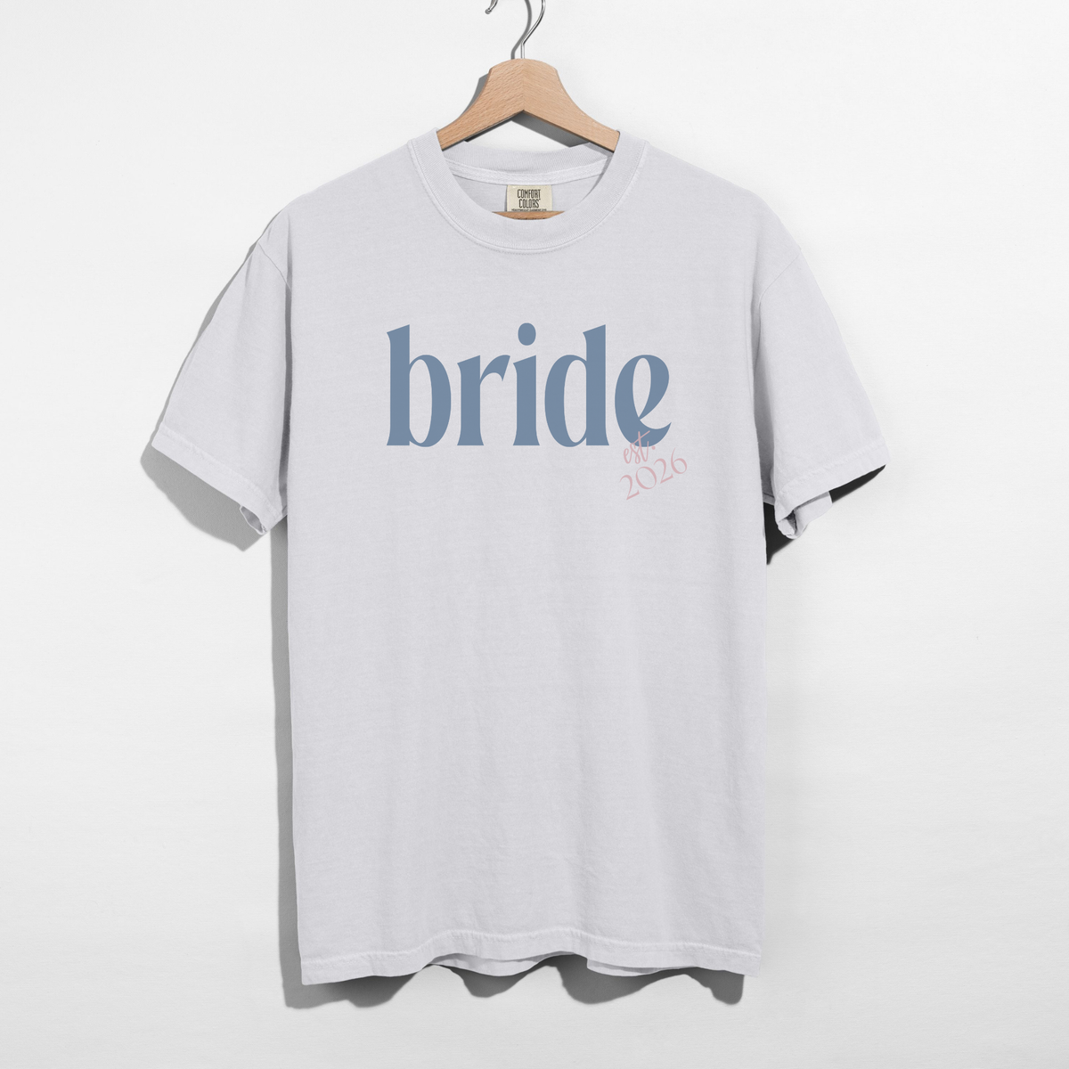 Bride Est. 2026 tee in white cotton with blue serif bride lettering and pink Est. 2026 detail
