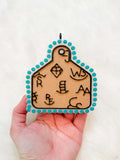 Cattle Tag Freshie in tan leather-look material with black cattle tag markings and turquoise beaded border