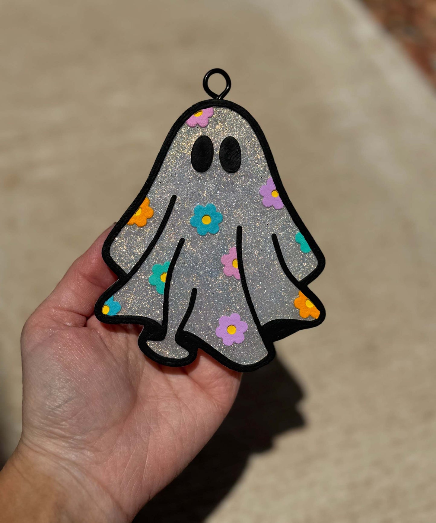 Daisy Ghost Freshie in glittery silver with black outline, oval eyes, and colorful daisy flowers