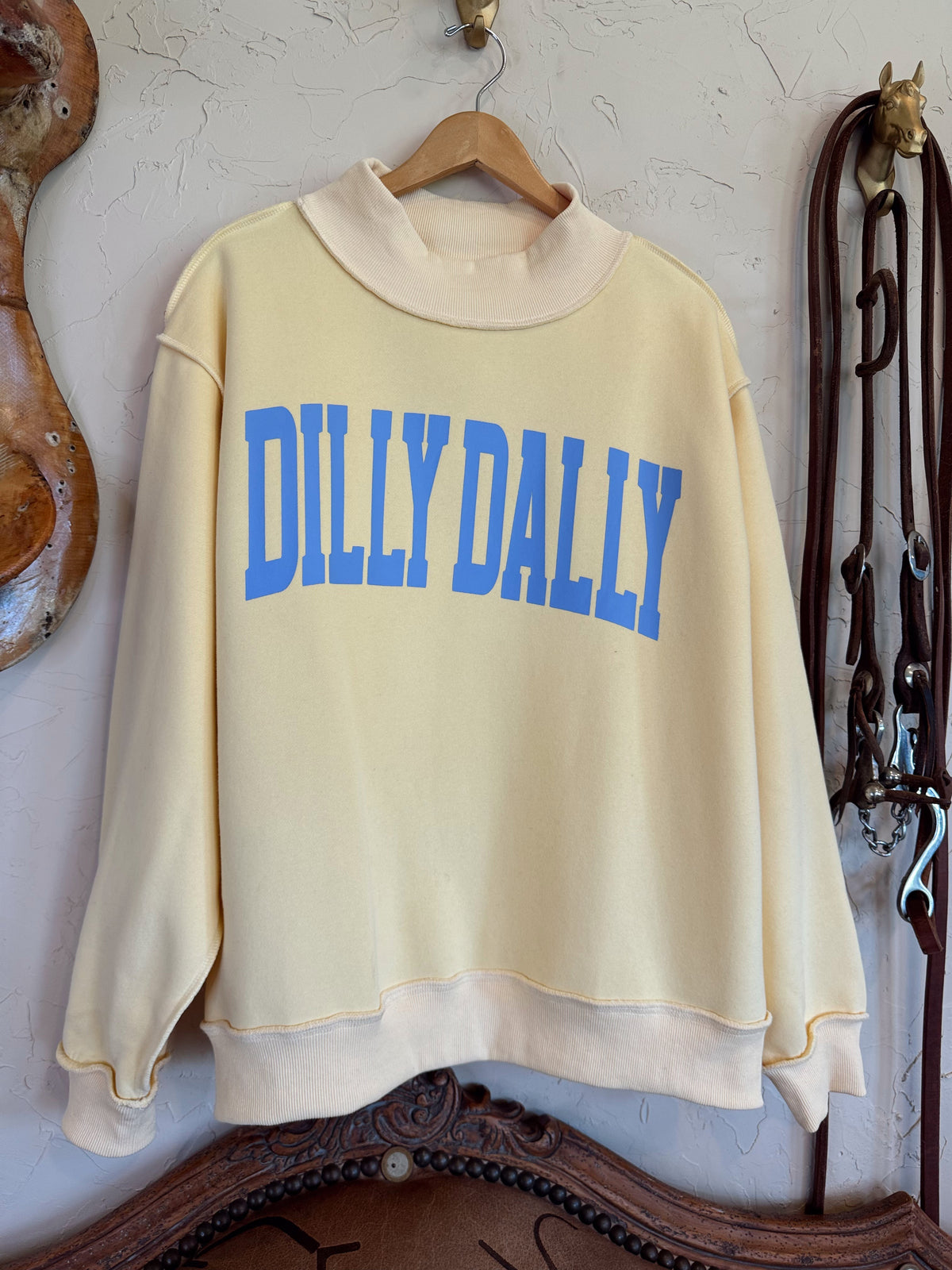Dillydally Mock Neck Sweatshirt in soft butter yellow cotton blend with baby blue "DILLY DALLY" graphic and cozy mock neck design.