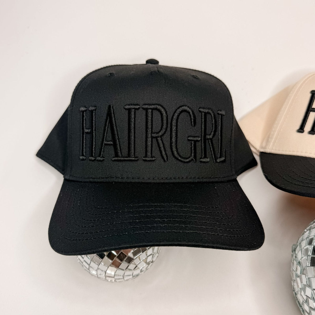 HAIRGRL - Trucker Hat in black with raised black puff embroidery on front, structured crown, and curved bill design.