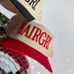HAIRGRL - Trucker Hat with cream front and red bill, featuring bold red 3D puff embroidery and adjustable snapback closure.