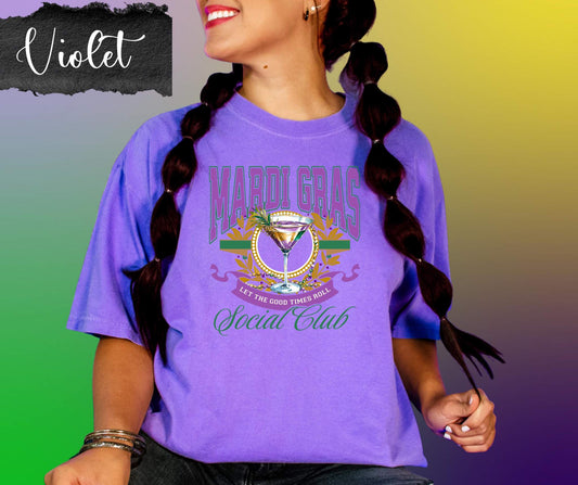 Person wearing a purple Mardi Gras t-shirt with colorful graphics and text on a gradient background.