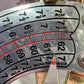 Mardi Gras FAT TUESDAY snapback hat not visible; image shows a close-up metallic roulette wheel with numbered sections