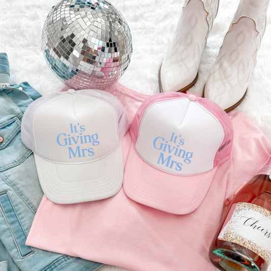 Mrs Trucker Hat in white and pink foam-front styles with blue “It’s Giving Mrs” lettering and mesh backs