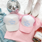 Mrs Trucker Hat in white and pink foam-front styles with blue “It’s Giving Mrs” lettering and mesh backs