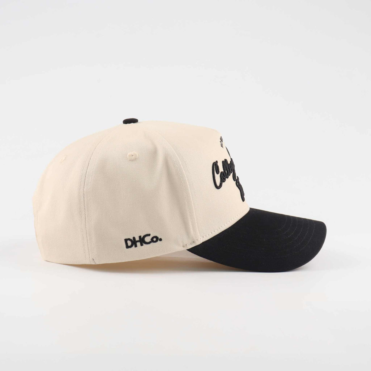 Pre-curved Trucker hat in beige and black with College Station script lettering and a curved black brim