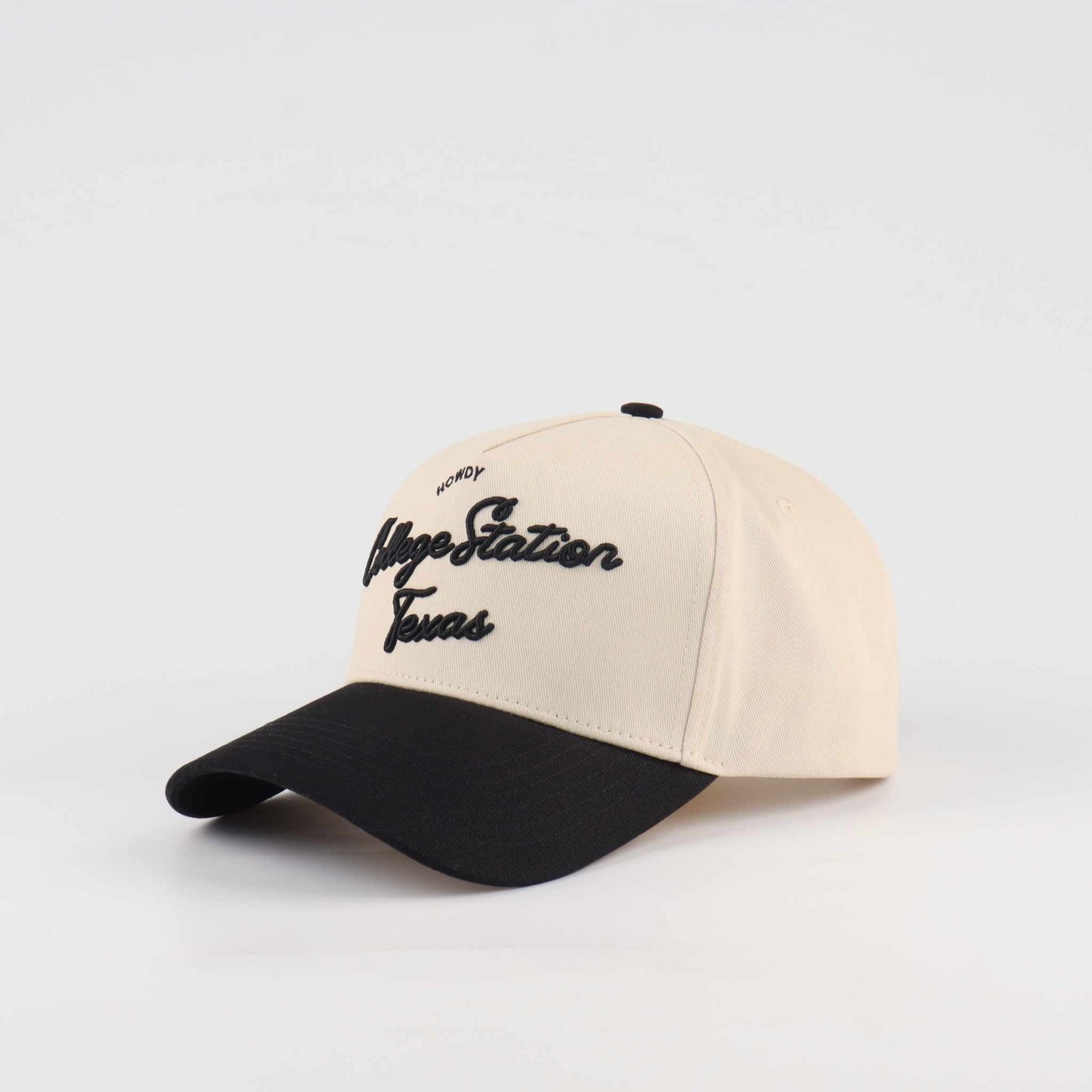 Pre-curved Trucker hat in beige and black with College Station script lettering and a curved black brim