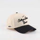 Pre-curved Trucker hat in beige and black with College Station script lettering and a curved black brim