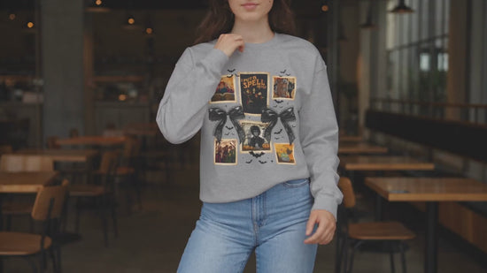 Woman modeling a Sport Grey crewneck sweatshirt featuring a vintage witch-themed Halloween collage with black bows, bats, pumpkins, and orange accents.
