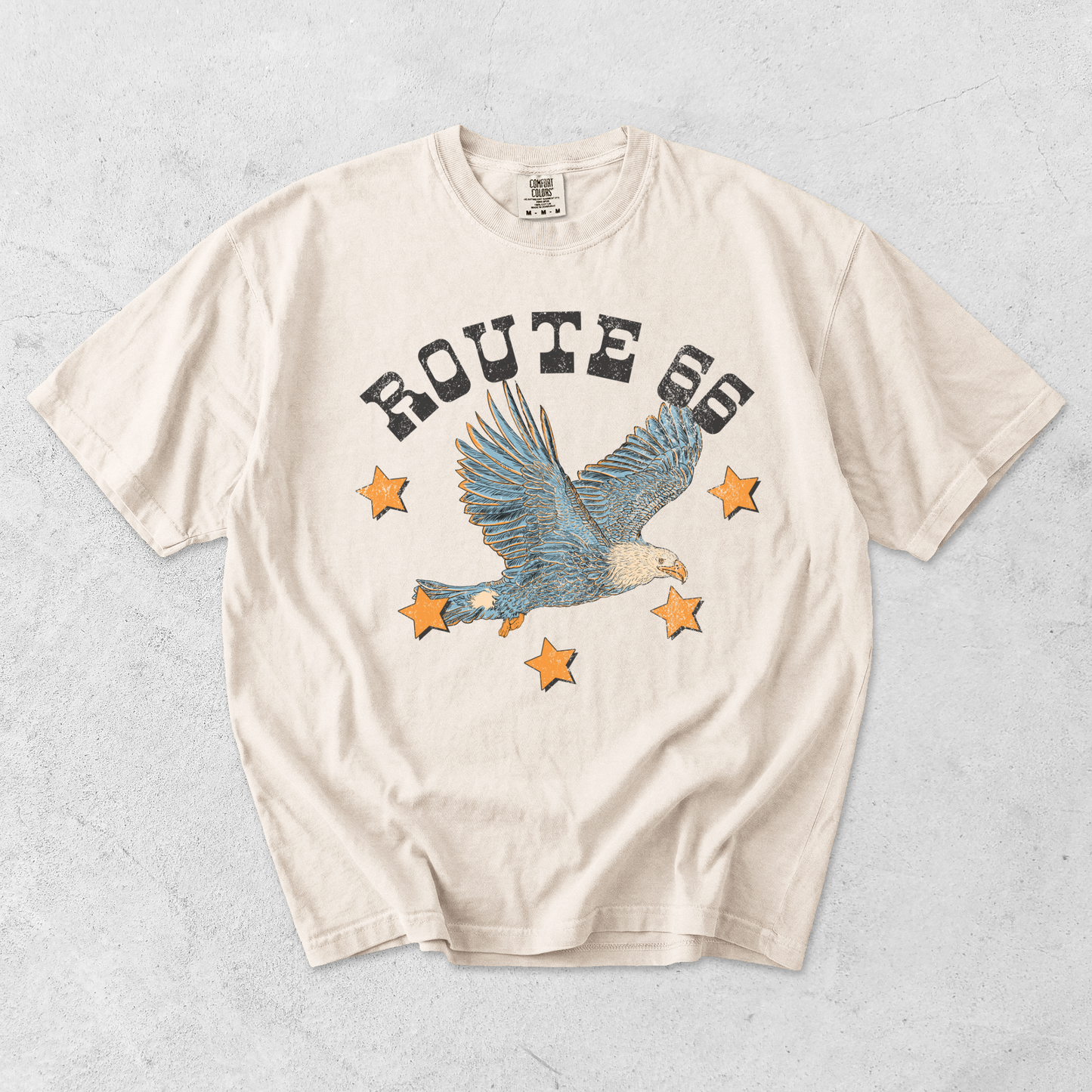 Route 66 eagle graphic tee in ivory cotton with distressed lettering, soaring eagle illustration, and orange stars