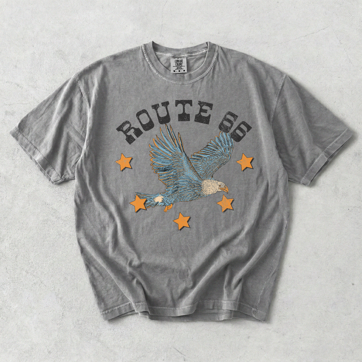 Route 66 eagle graphic tee in washed grey cotton with distressed lettering, soaring eagle design, and orange stars