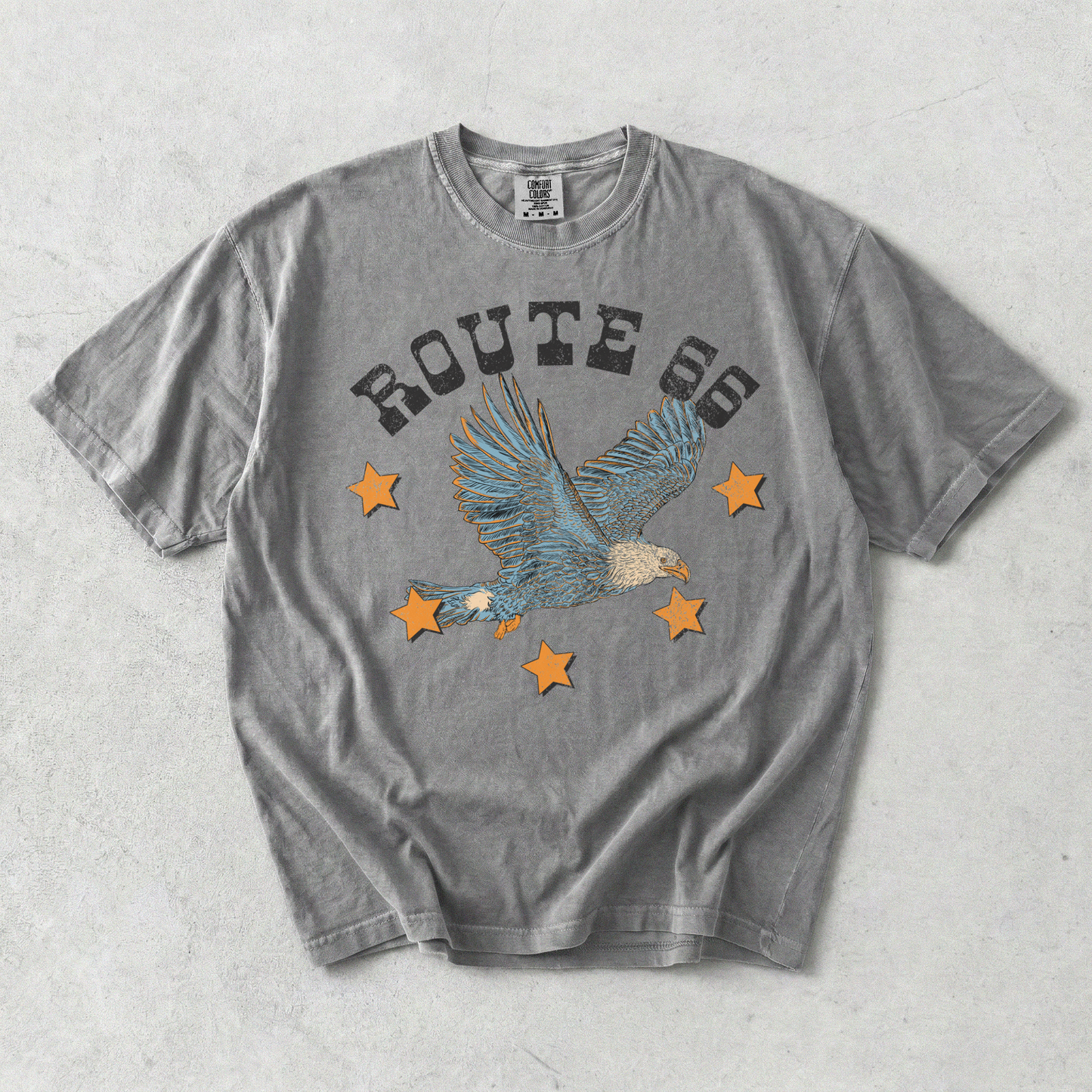 Route 66 eagle graphic tee in washed grey cotton with distressed lettering, soaring eagle design, and orange stars