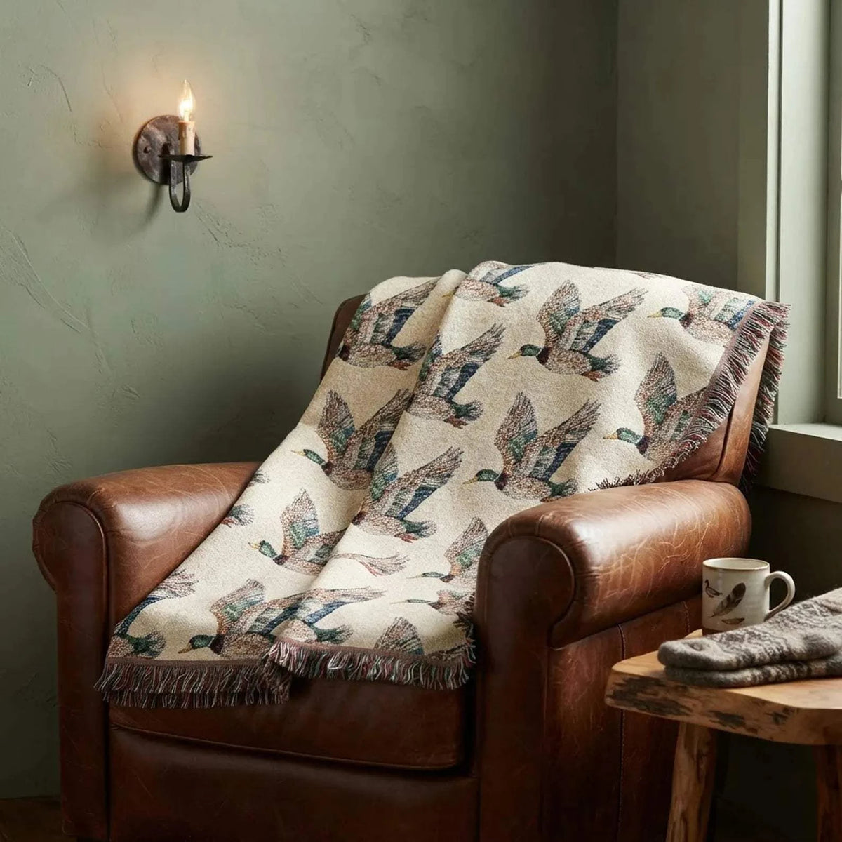 Rustic Cabin Throw featuring a woven Flying Mallard Duck pattern in earthy tones with colorful fringed edges draped over a brown leather chair