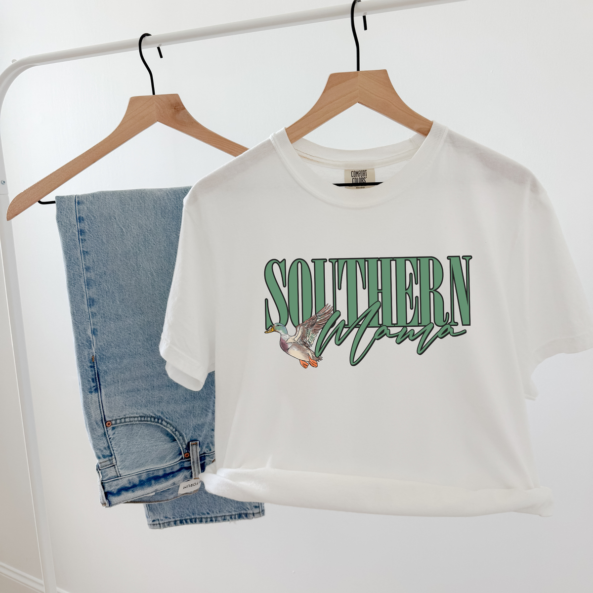 Southern Mama Tee in white cotton with green collegiate lettering, script detail, and illustrated flying mallard graphic