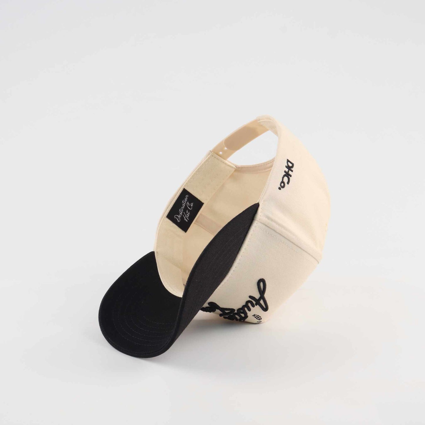 The "Austin" Script Hat, beige cotton trucker cap with black brim and embroidered black script lettering