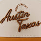 The Austin Script Hat, beige trucker cap with raised orange-brown embroidered Austin script and Keep It Weird text