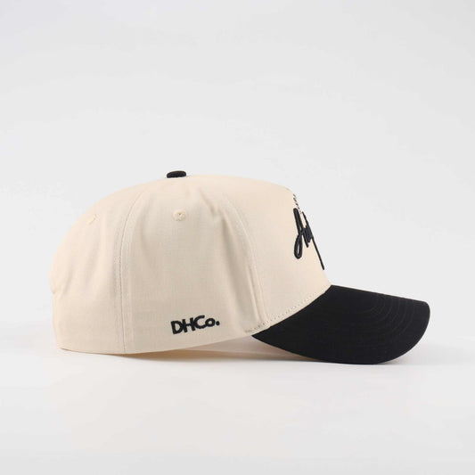 The "Austin" Script Hat in cream cotton with a black pre-curved brim and embroidered script logo