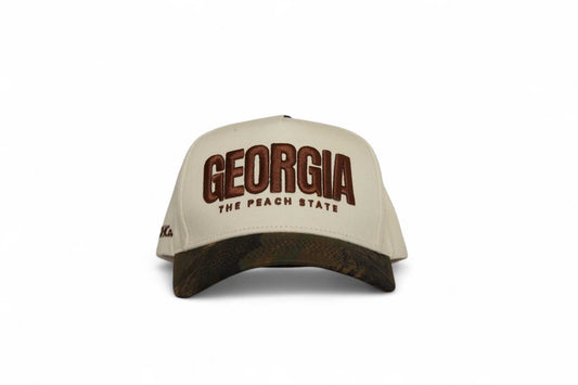 The Camo Georgia Snapback beige trucker hat with brown camouflage brim and embroidered Georgia peach state lettering